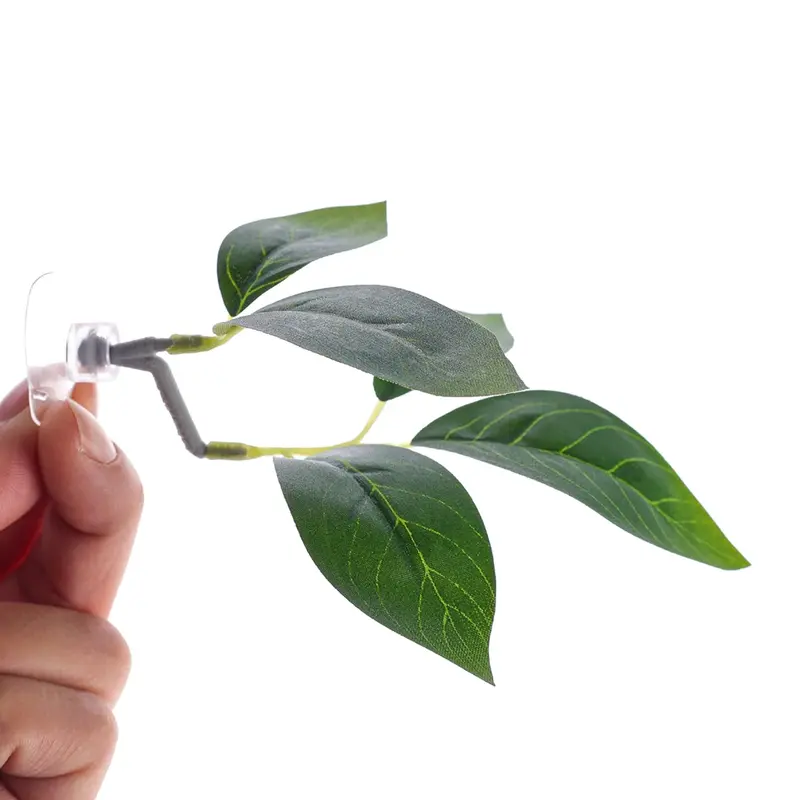 Ornement Plante artificielle d'aquarium verte en plastique, tenue par une main, ventouse transparente.